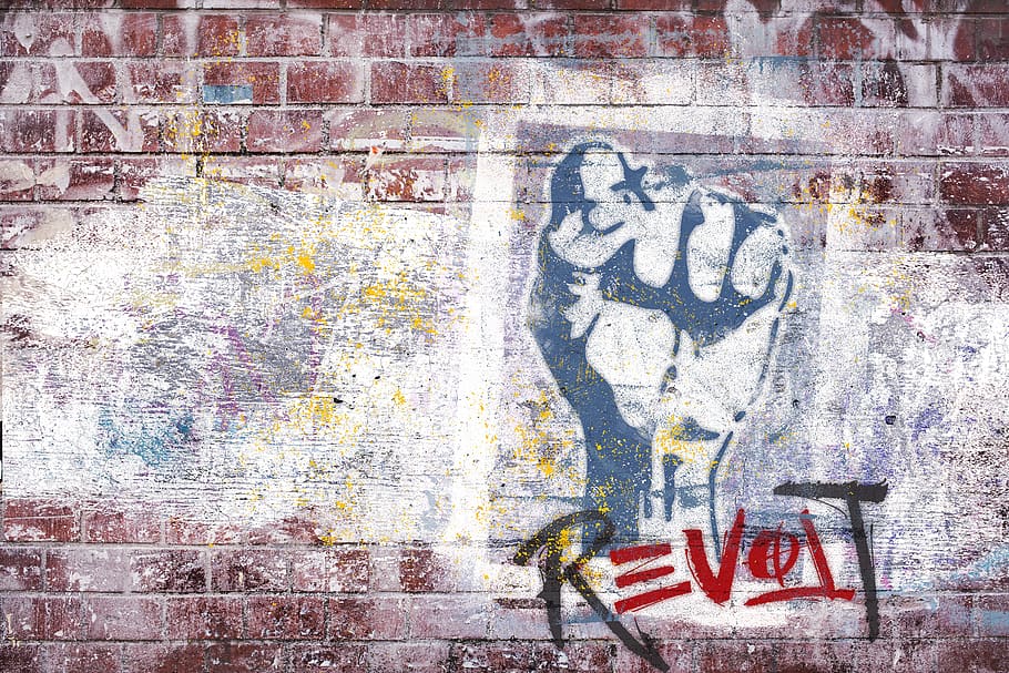 Arts for social change . Graffiti of a first up and the word Revolt on a brick wall